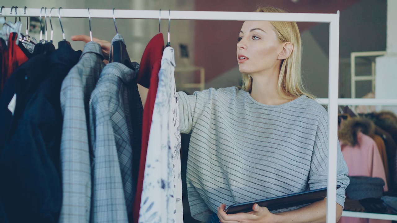 Adult woman browsing clothes in a fashion store with a tablet.